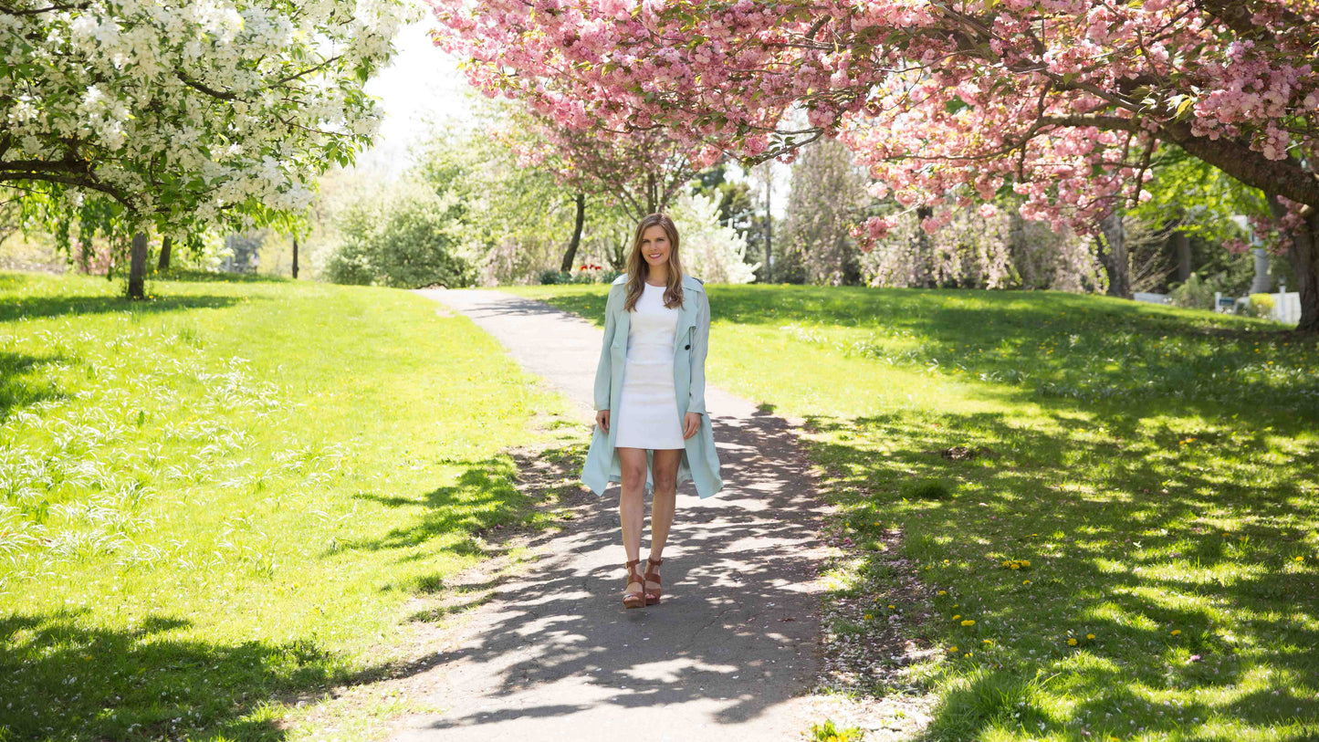 Woman walking under cherry blossom trees in a park